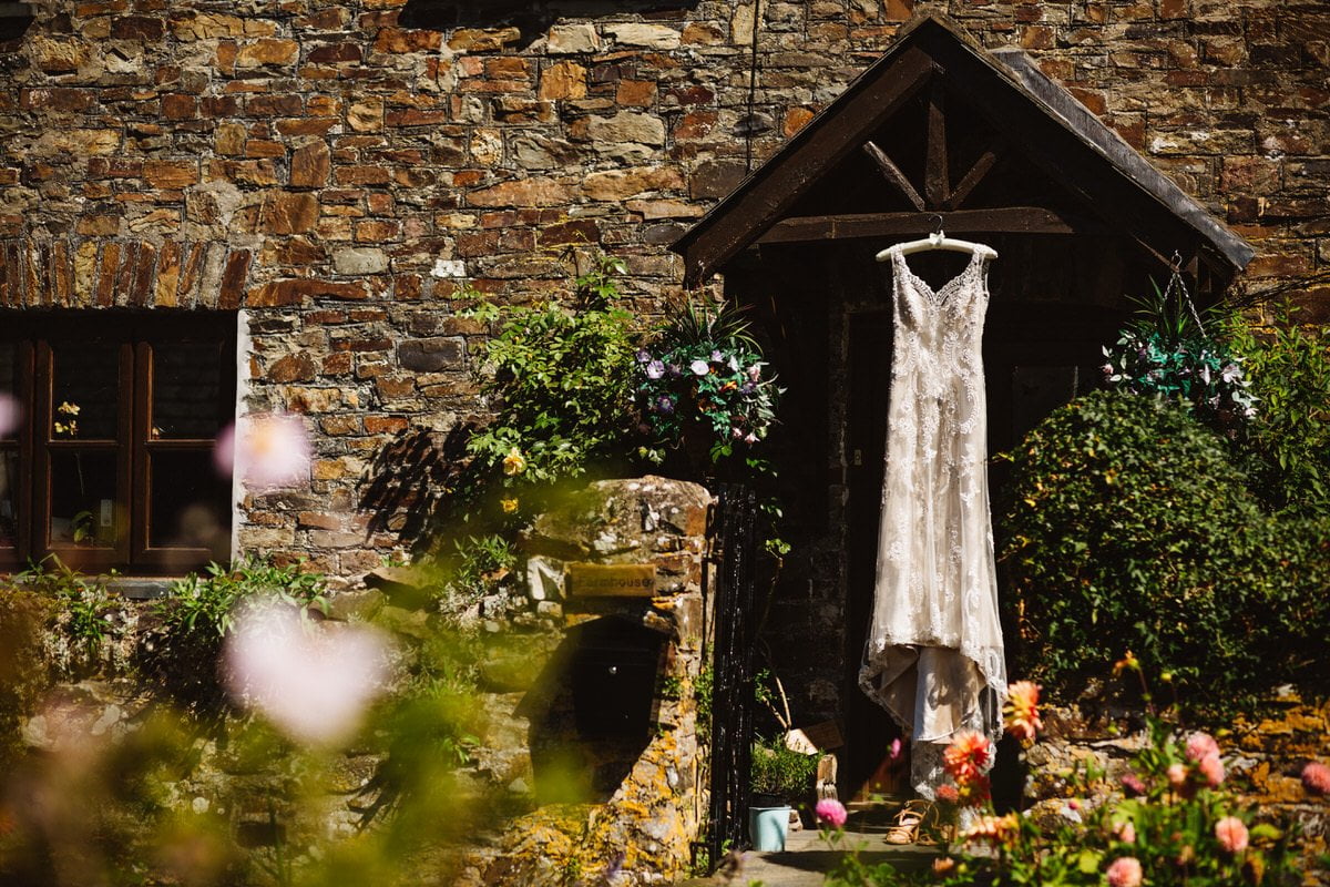 Stunning ivory lace dress, hanging from a wooden beam doorway.