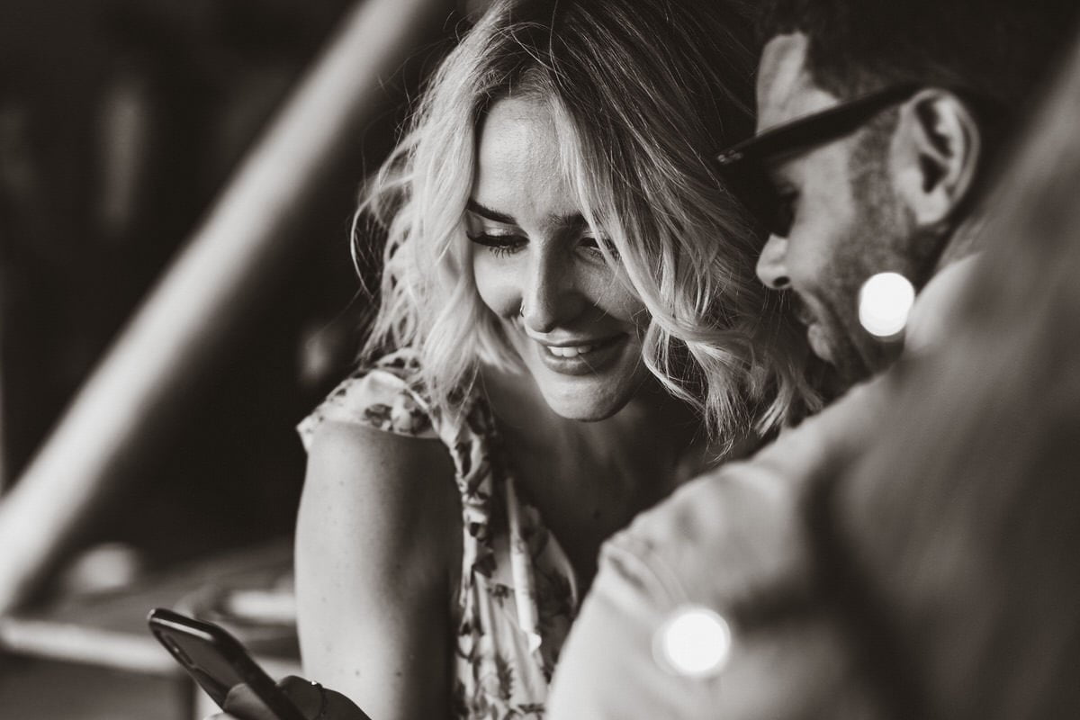 Black and white photograph of a couple smiling at a phone. Taken at Country Ways Devon