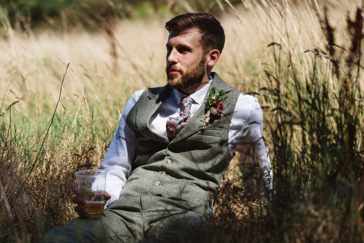 James sitting down in the long grass with a beer