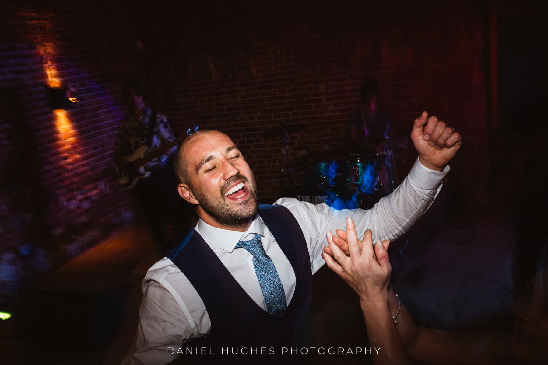 Groom dances with arms raised, singing with his eyes closed.